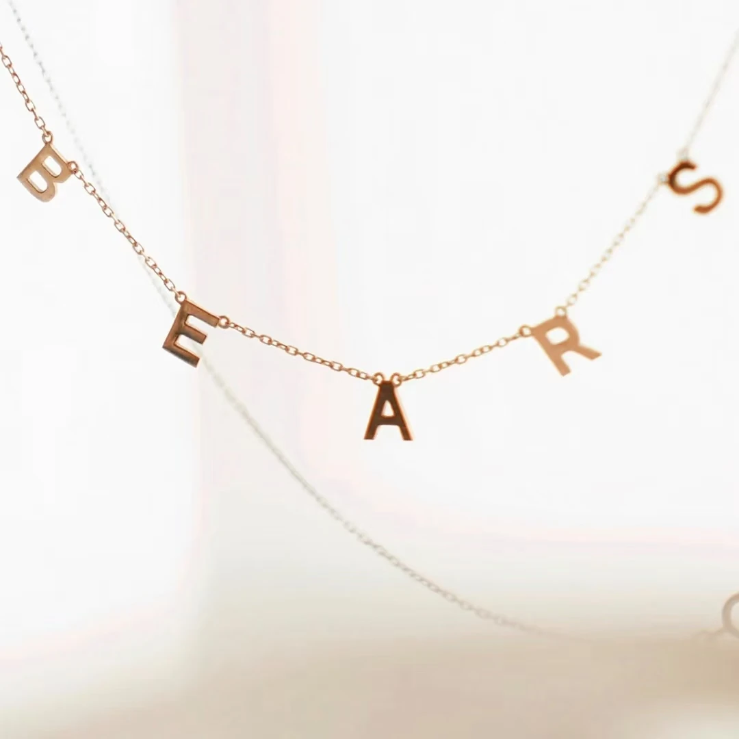 Necklace with individual gold-colored letter pendants shown as a metal cutting sample