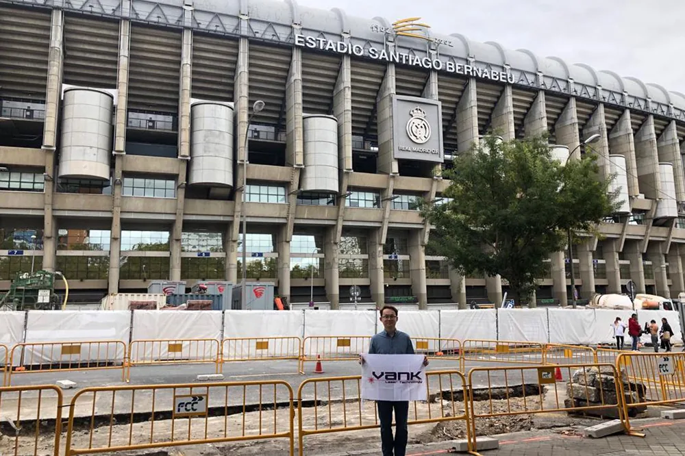 Person holding a VANK LASER banner outside a stadium
