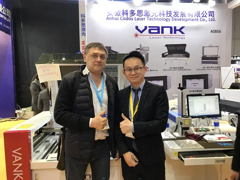 Vank Laser booth with two visitors beside displayed laser equipment at an advertising exhibition.